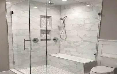 Custom marble tile shower with bench and glass enclosure